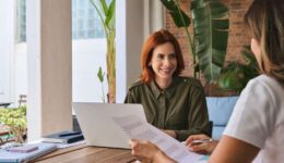 Young happy woman manager consulting client working in office using laptop.