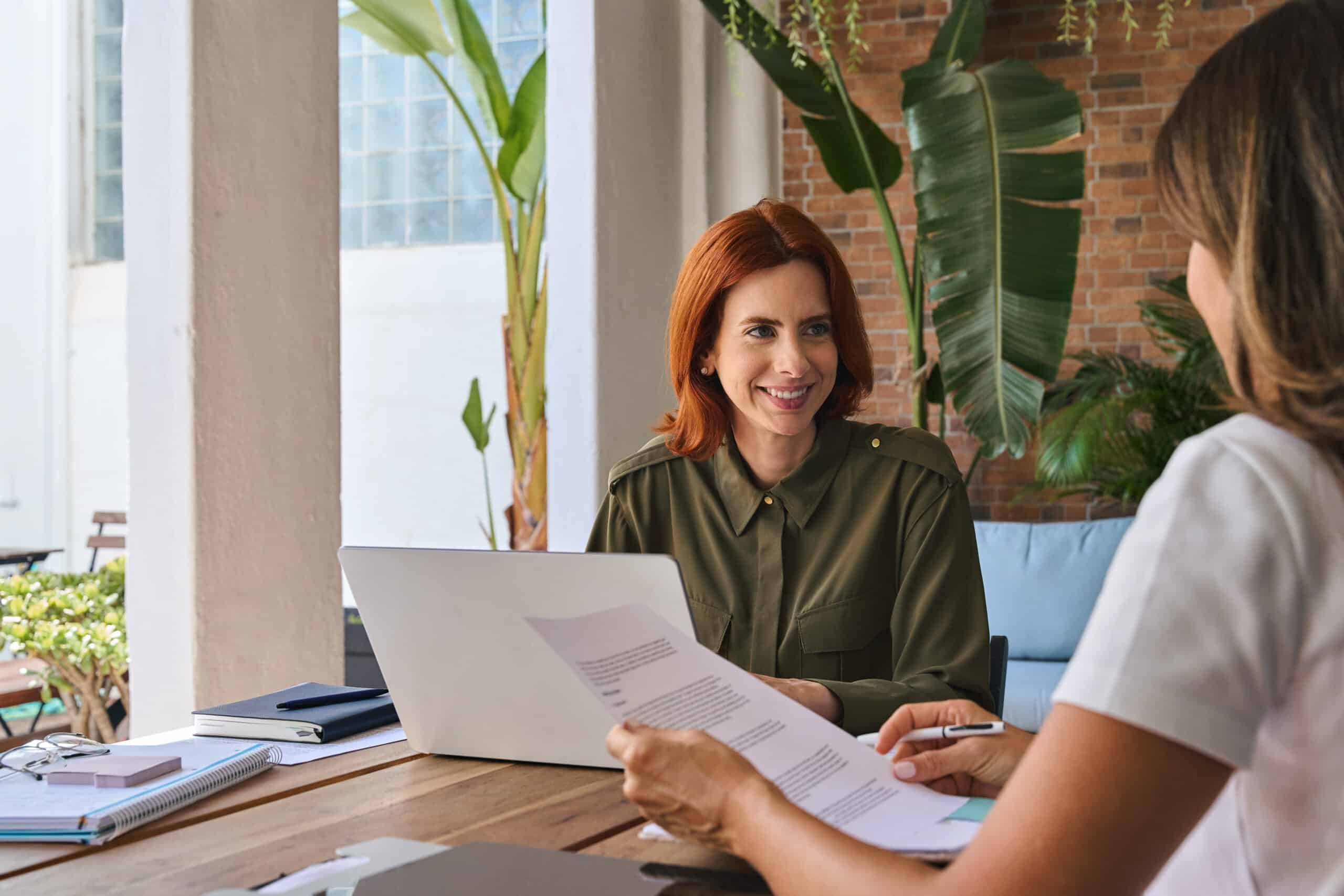 Young happy woman manager consulting client working in office using laptop.