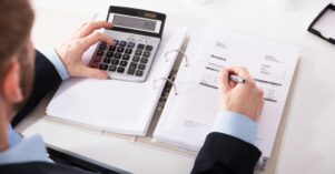Businessperson Checking Invoice With Calculator Businessperson Checking Invoice With Calculator