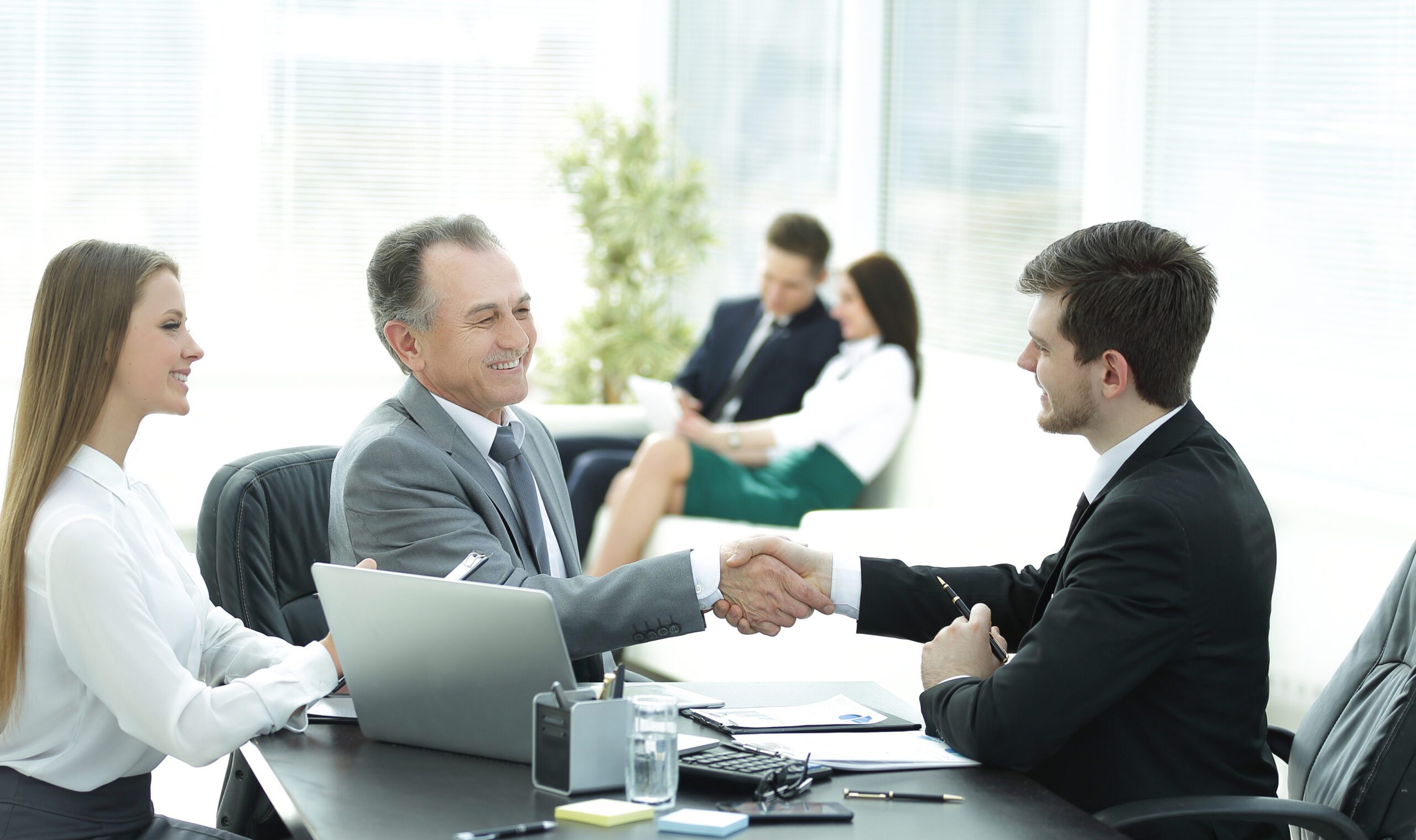 handshake business people behind a Desk in the office handshake business people behind a Desk in the office